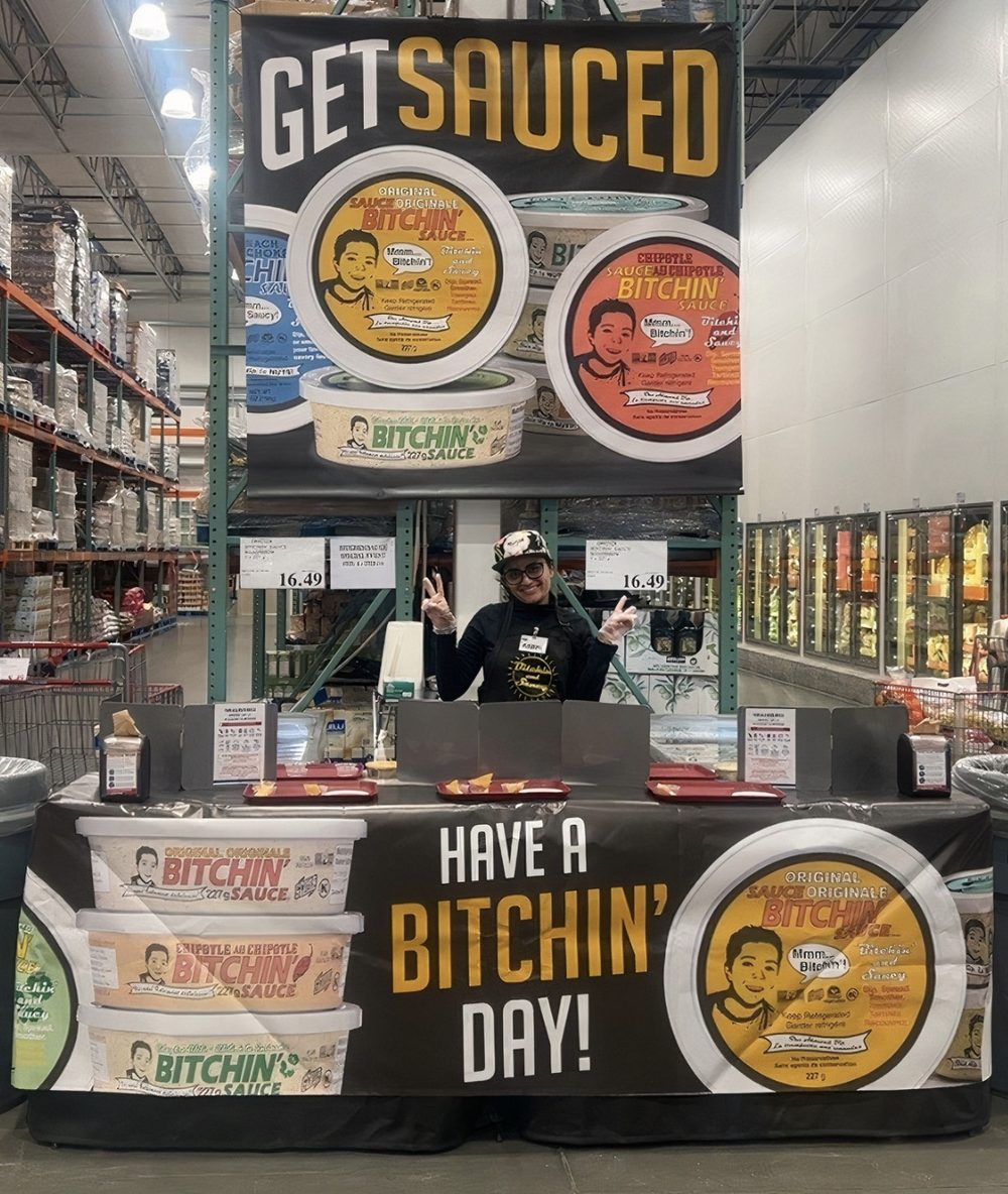 Bitchin' Sauce Costco Roadshow booth with a team member and a Get Sauced banner